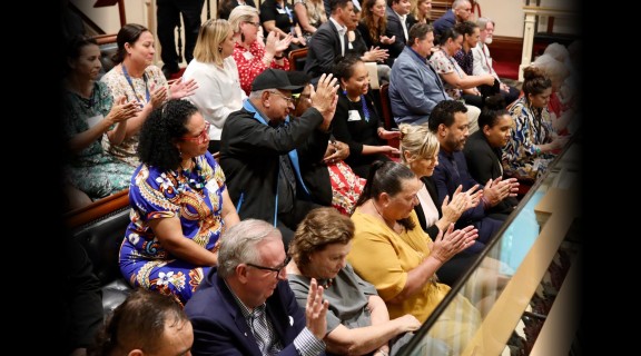 A group of people sitting in an audience clapping.