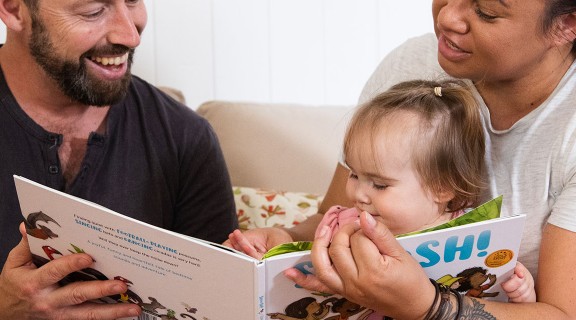 Family reading to small child at home