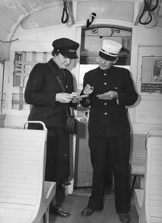 New tram conductor recruit (Mrs J. Burgess, left) in training on a tram with male conductor (right), 1942