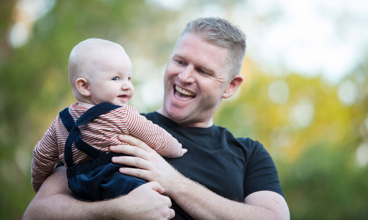 Father holding a small baby outside. 