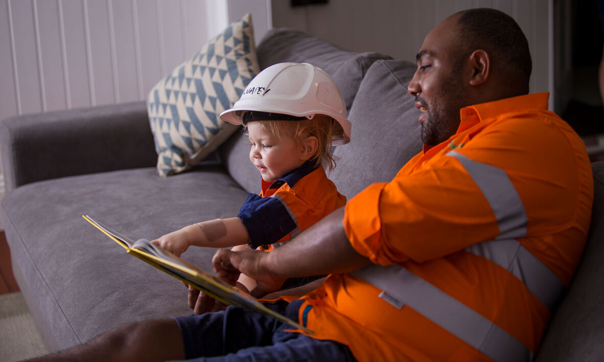 Father and child wearing high vis and reading a picture book together.