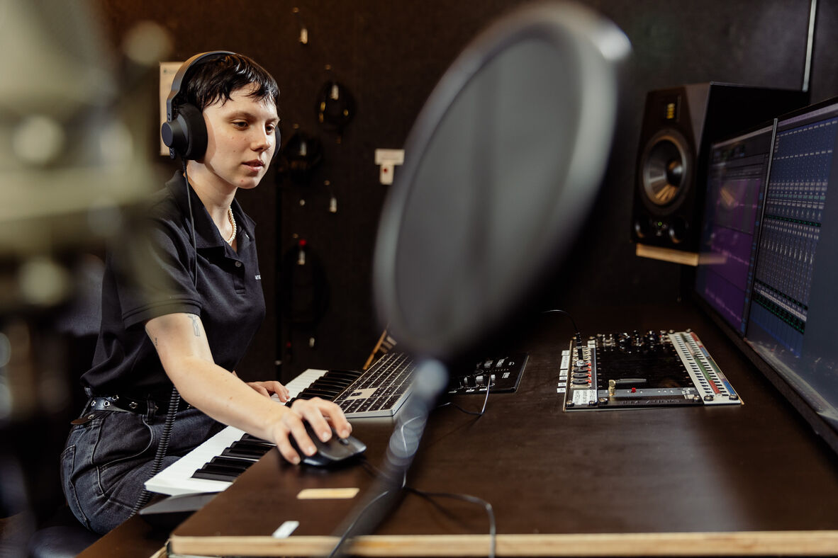 A photo of someone in a recording studio at a mixing desk