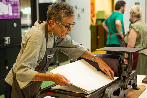 A woman learns how to use an old traditional press 