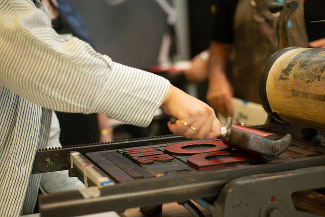 A participant inks a plate on the rolling press with red ink
