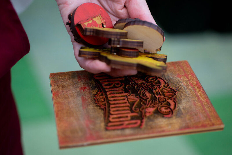 A persons hand holds a range of shapes laser cut and etched. 