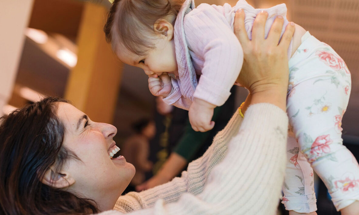 Mother holding up baby above herself and smiling.