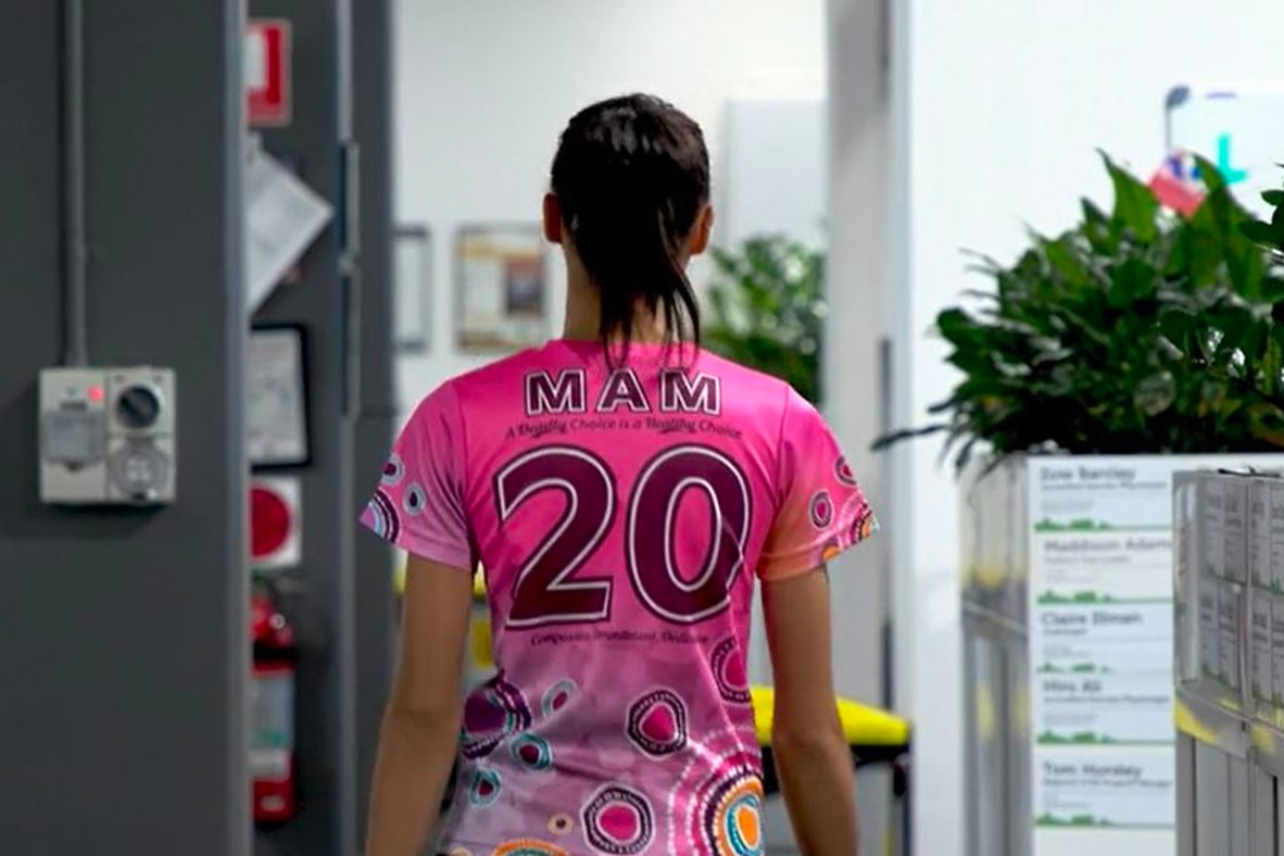 A still from a video showing the back of a person wearing a number 20 "Aunt Pam" jersey.