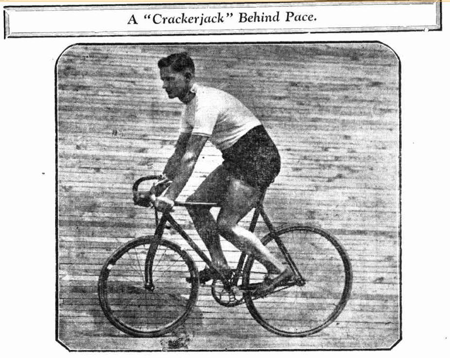 Black-and-white printed image titled “A ‘Crackerjack’ Behind Pace,” showing a male cyclist riding a track bicycle. He wears a short-sleeved shirt and shorts, leaning forward over the handlebars. The image appears in a publication, with a bordered frame and textured background suggesting motion or speed.