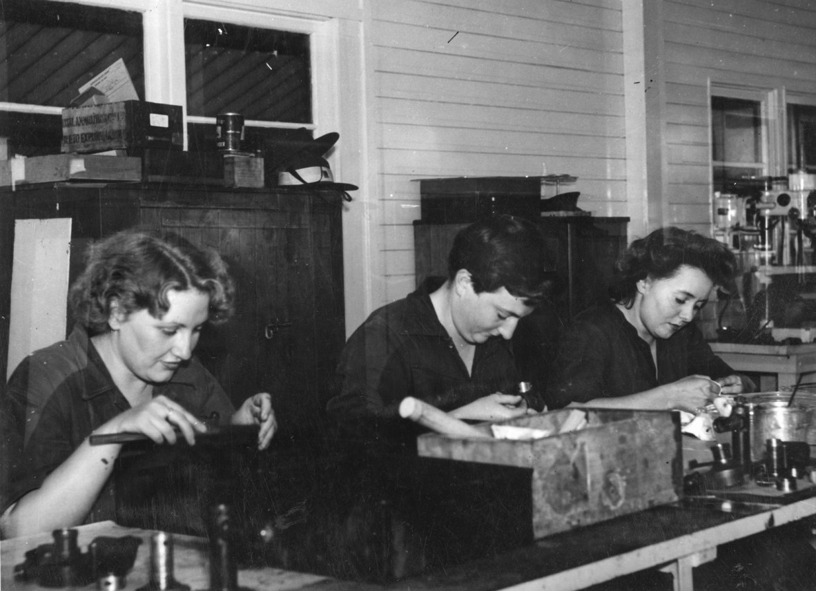 Old photograph of women working at a desk in a factory.