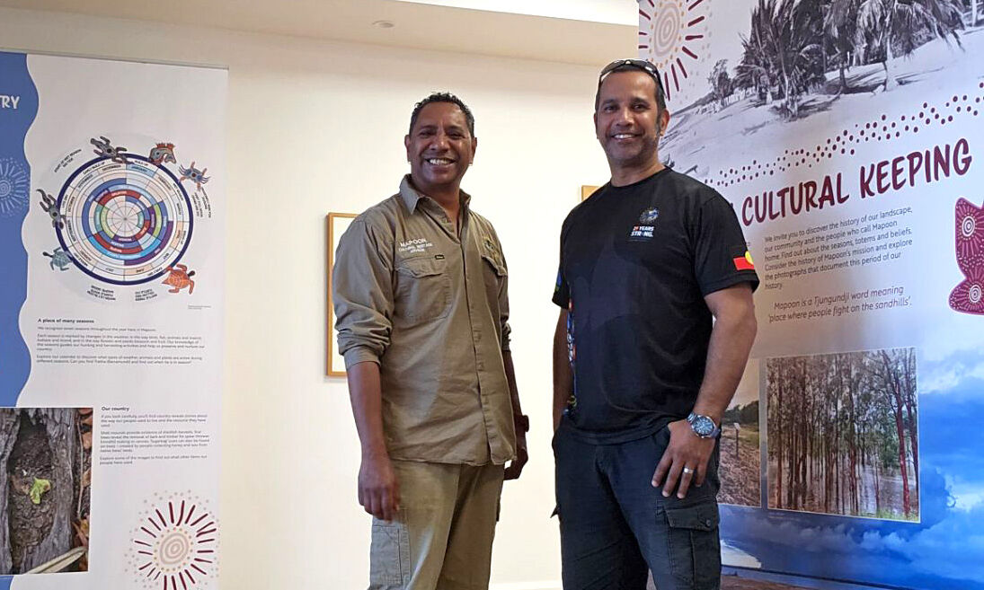 Two men standing together and smiling.