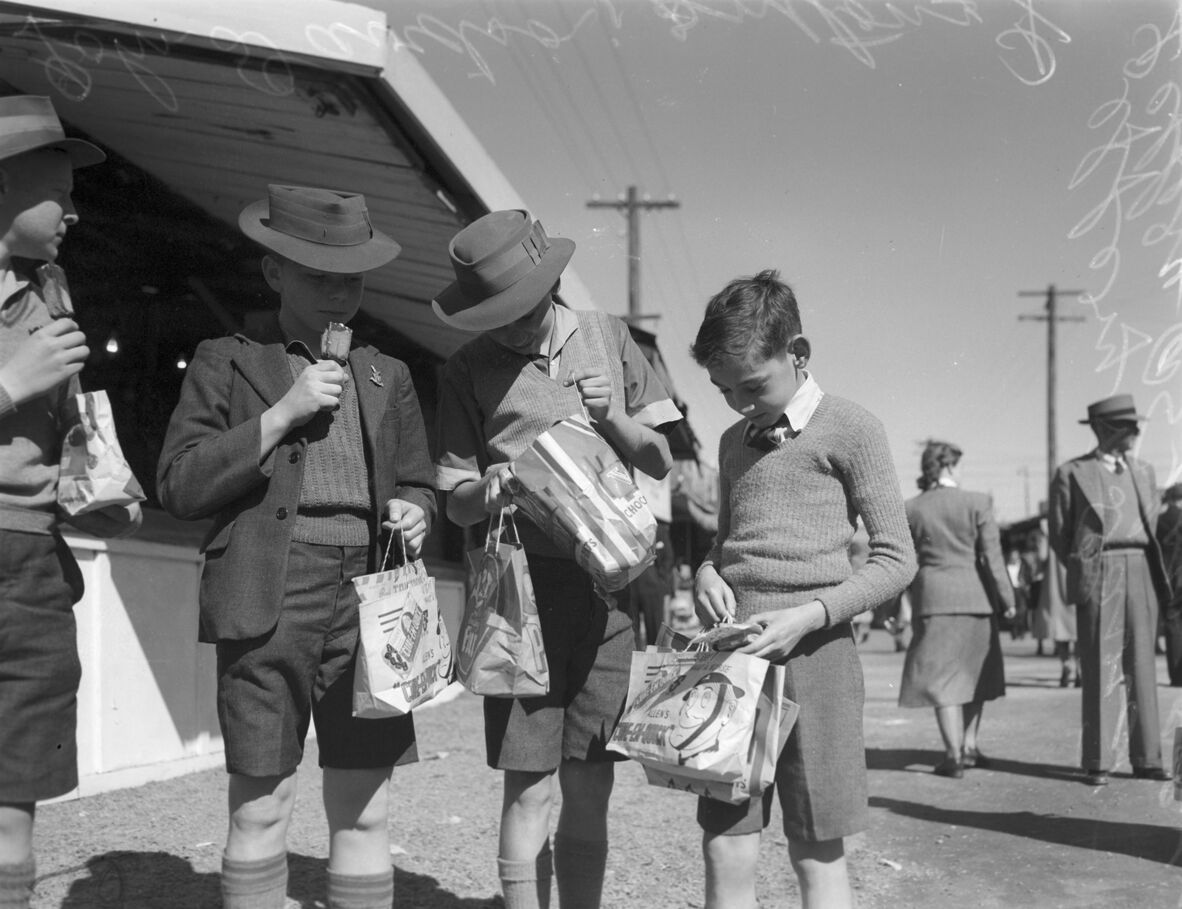 Black and white photo of a group of boys looking at their showbags in 1949