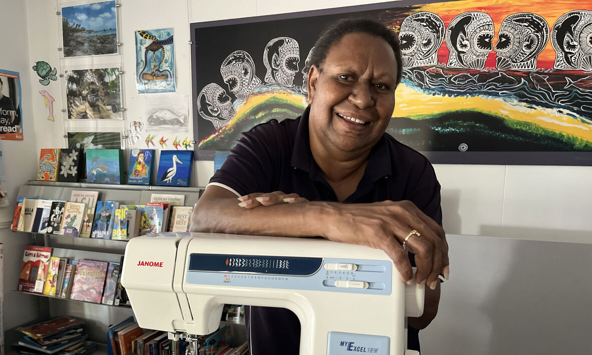 Person smiling and leaning on a sewing machine.