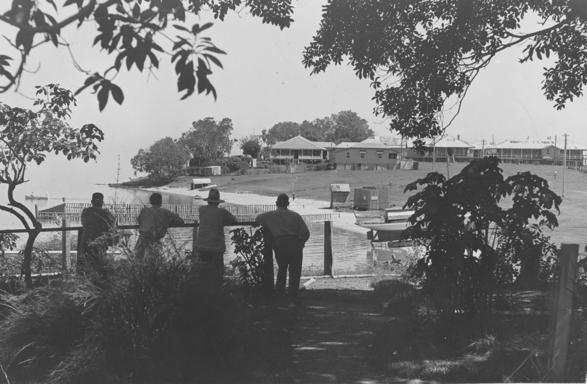  Four men leaning on a fence overlooking the benevolent asylum at Dunwich, Queensland, 1938
