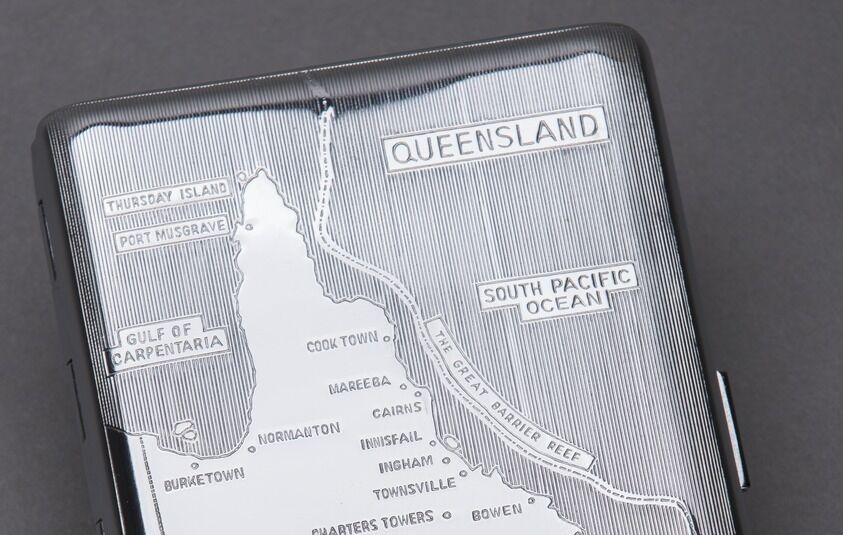 A polished silver cigarette case engraved with a map of Queensland.