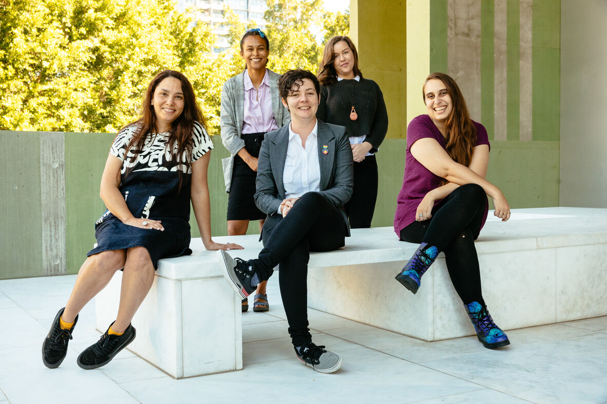 Five people sitting at State Library together. They are sitting on the QLDTerrace and are all smiling.