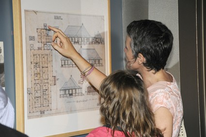 Two exhibition visitors looking at framed architectural plan