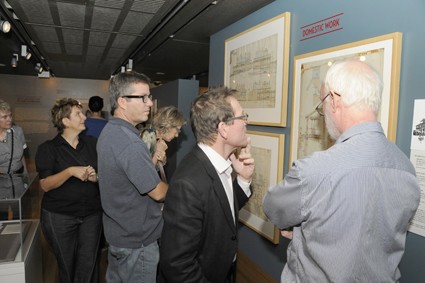 Group of exhibition visitors looking at framed architectural plans
