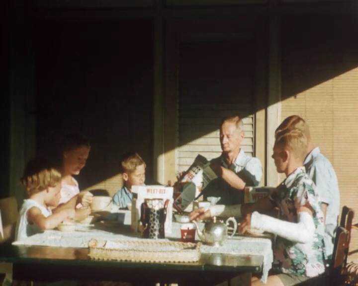 a family sits at a table for breakfast in the sun