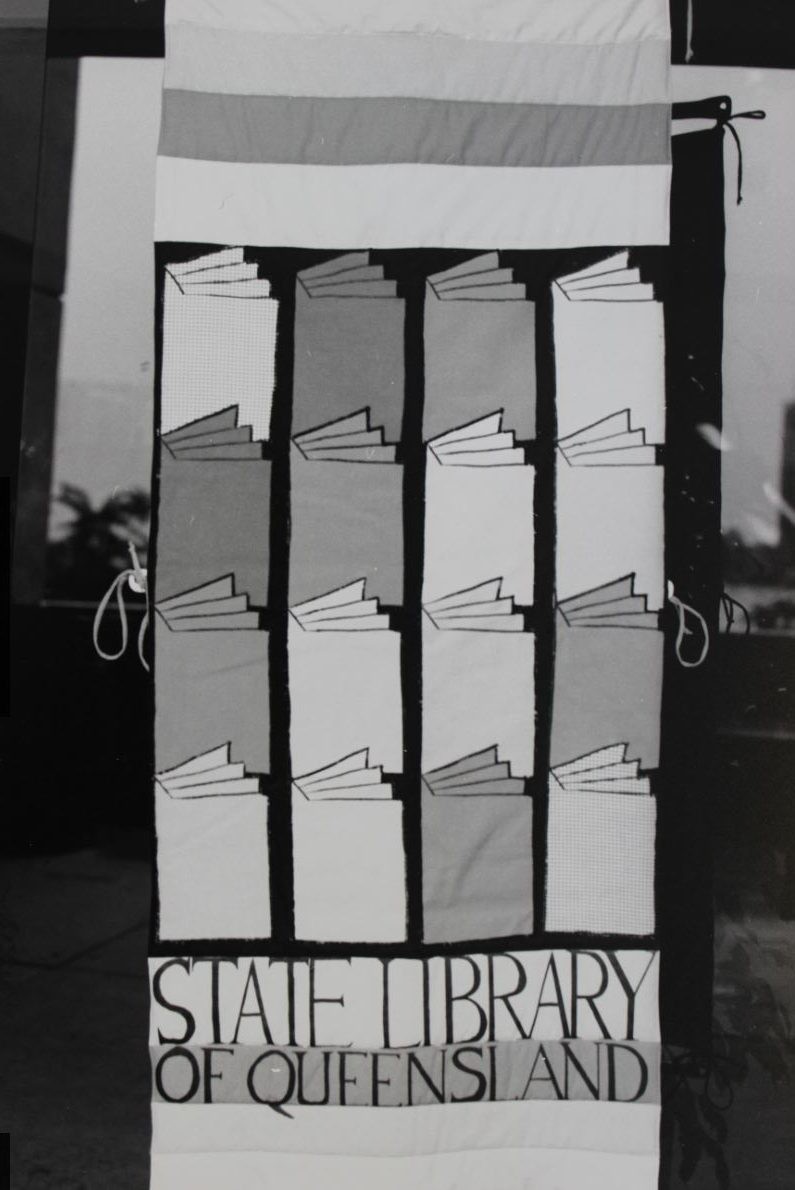 black and white image of a banner with columns of books reading State library of Queensland