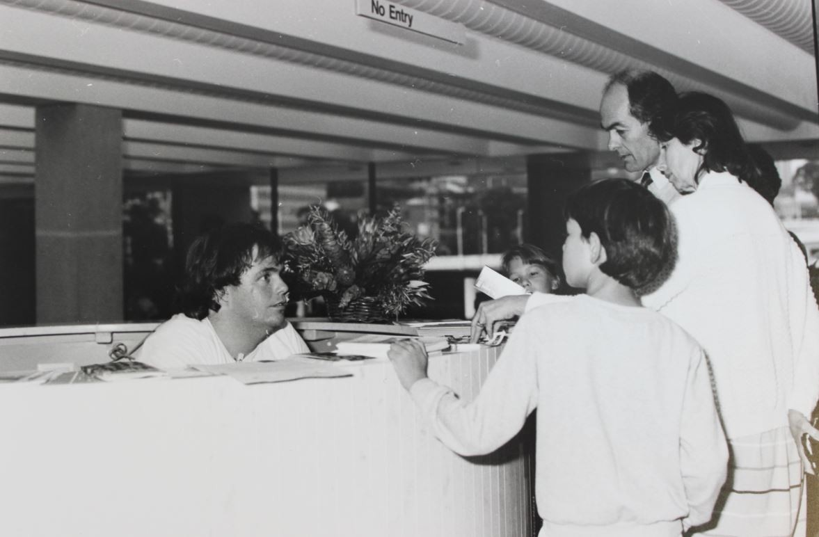 people stand in front of a service desk at the State Library