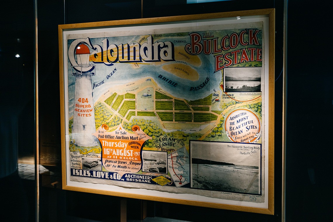 1917 real estate map advertising land for sale at the Bulcock Estate in Caloundra. The coloured map features an illustration of a lighthouse and four black and white photographs of the locality. The central feature is an illustrated map of the Caloundra Explanade and the waters of the Bribie Passage.