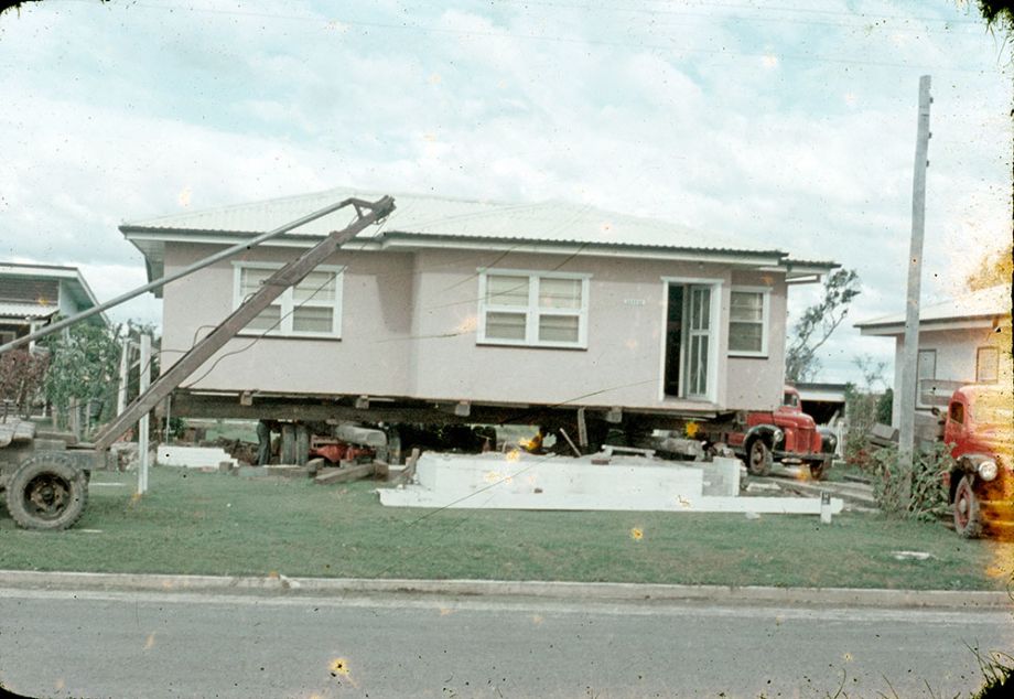 House being jacked up for removal, ca1959. A house being lifted with machinery.