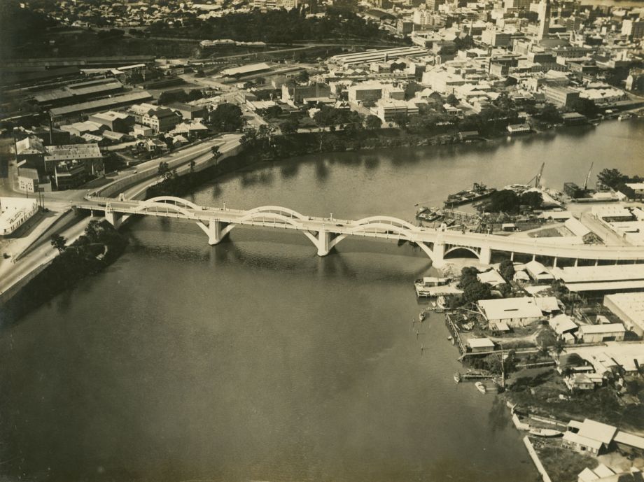 Aerial photo of the bridge taken soon after the opening, showing detail of the cityscape and roads on north and south sides of the river.